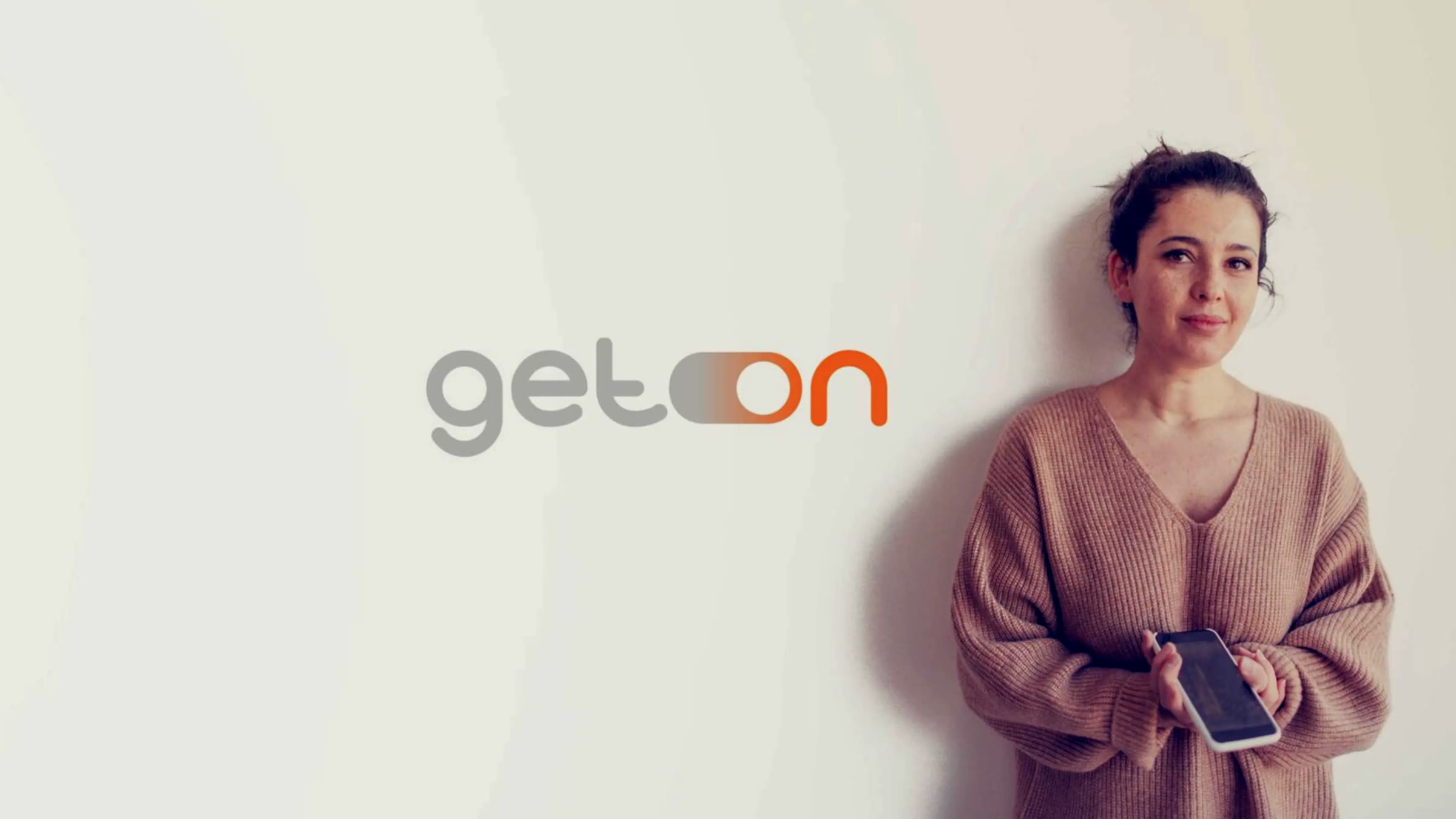 GET.ON, Frau mit Smartphone vor heller Wand neben dem neuen Logo