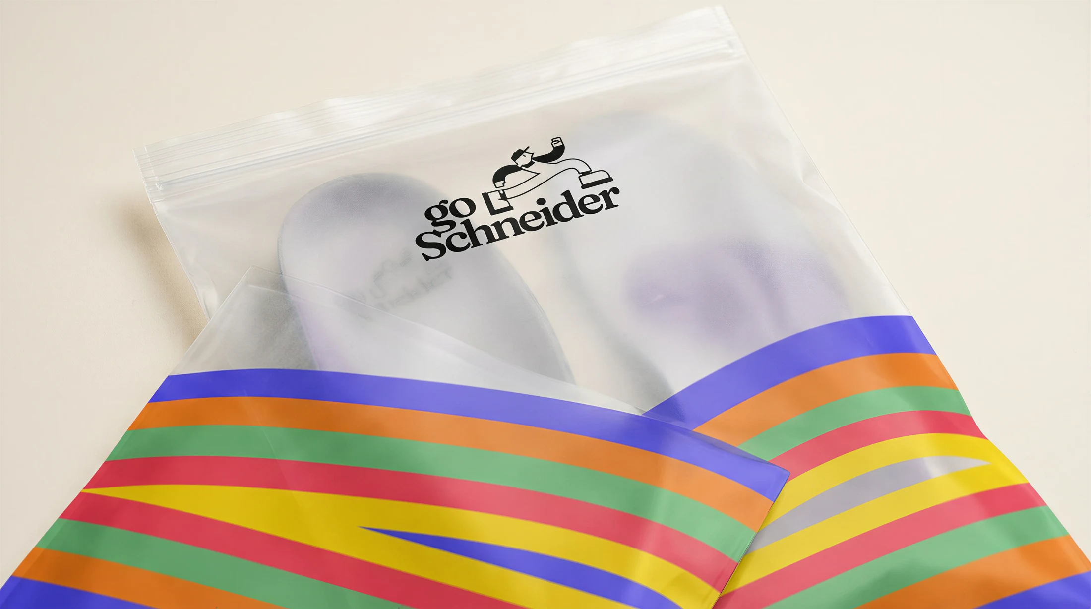 goSchneider Verpackungs-Mockup mit Einlagen im transparenten Beutel und farbiger Regenbogen-Bodenform