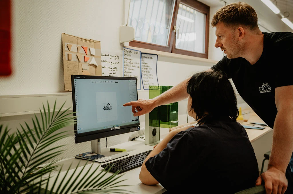 Dennis und Kollegin stimmen den digitalen Ablauf am Computer ab