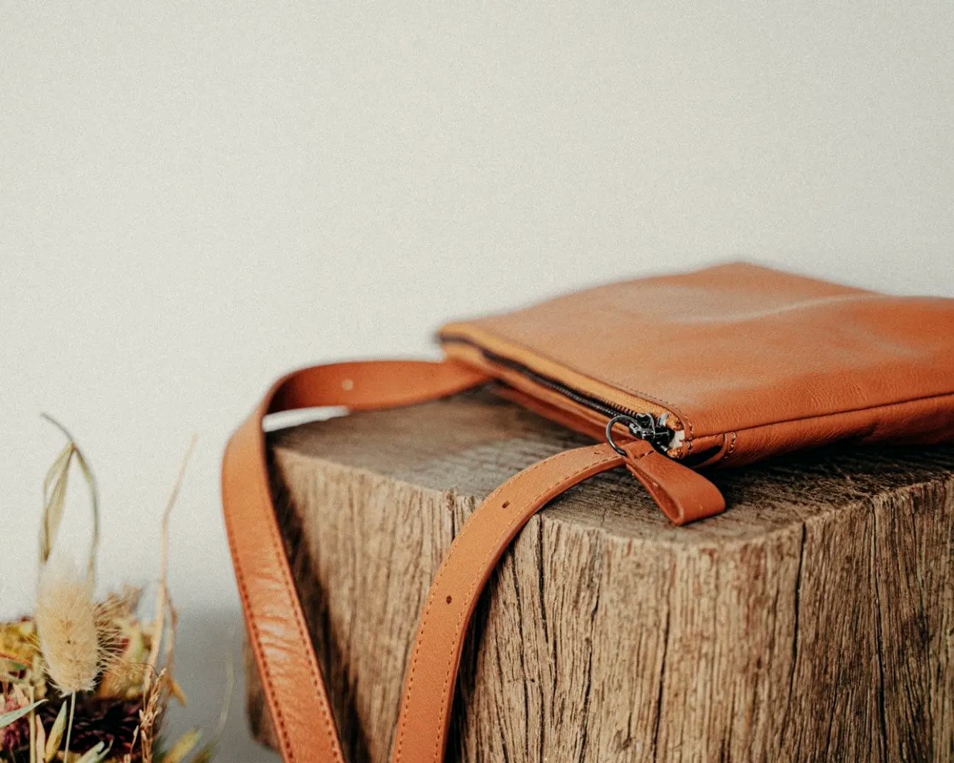 mine mina, Ledertasche in Cognac auf einem Holzblock