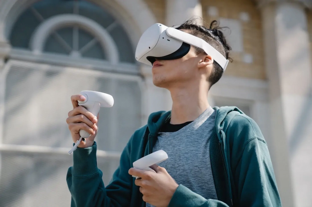 Early Adopter sind offen für Innovationen, wie zum Beispiel VR-Brillen. Auf dem Bild ist ein junger Mann zu sehen, der eine solche VR Brille trägt und Controller in den Händen hält.