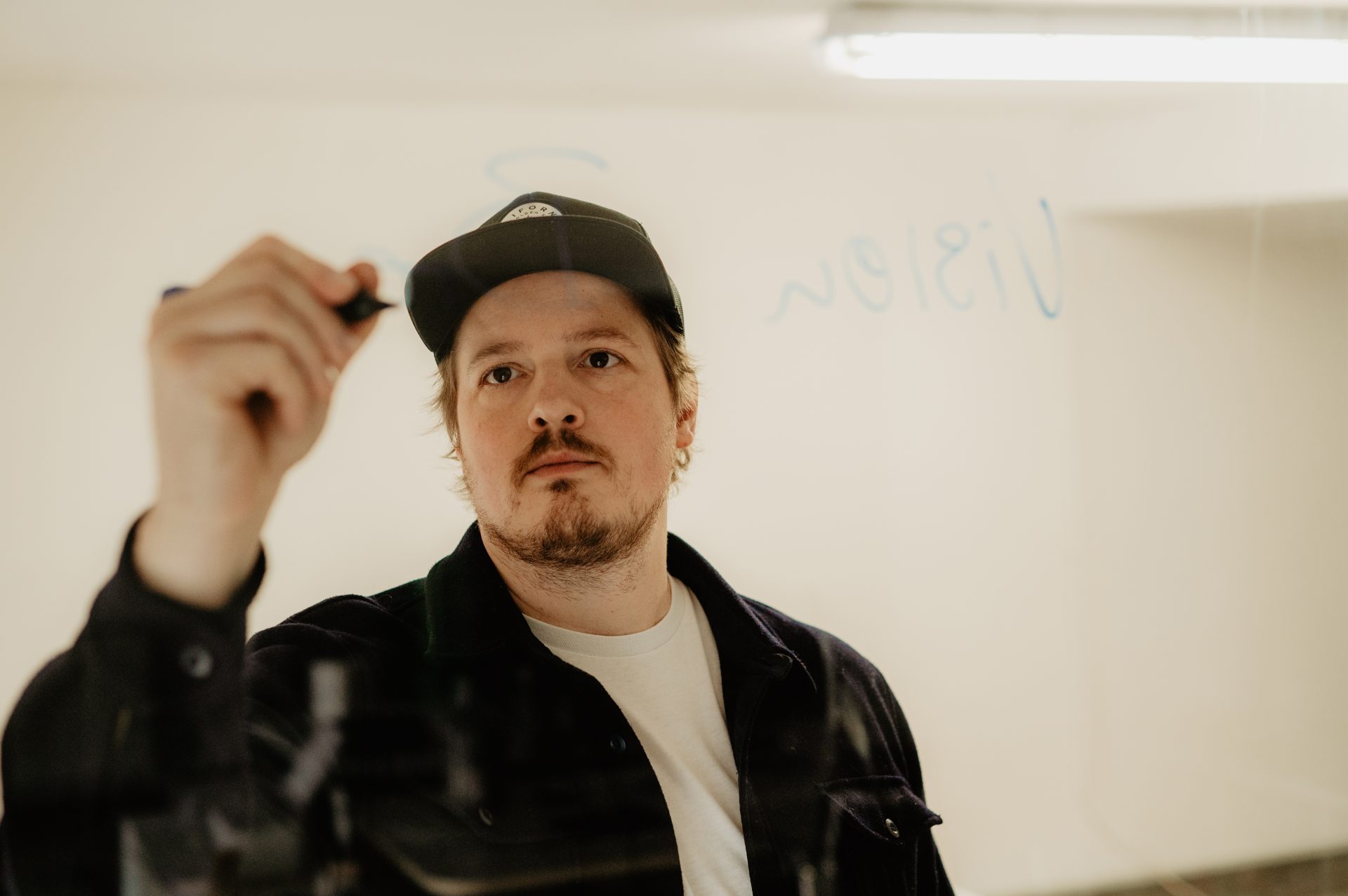 Wolfram, Gründer von CONCRETE - Brandbuilding GmbH schreibt auf Scheibe eine Markenstrategie